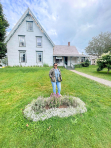 Marie in front of house by flower garden